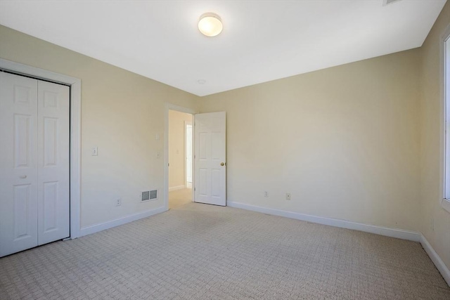 unfurnished bedroom with light colored carpet and a closet