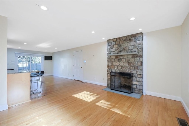 unfurnished living room with a large fireplace and light hardwood / wood-style flooring