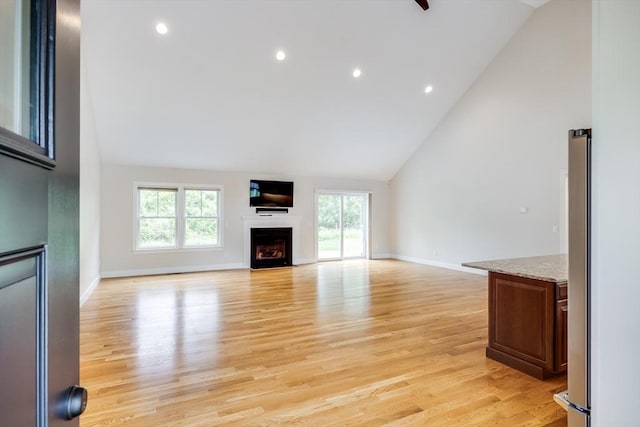 15 Hydrangea Cir, Falmouth, MA 02536 - unfurnished living room featuring healthy amount of natural light, high vaulted ceiling, light wood-type flooring, a fireplace, and baseboards