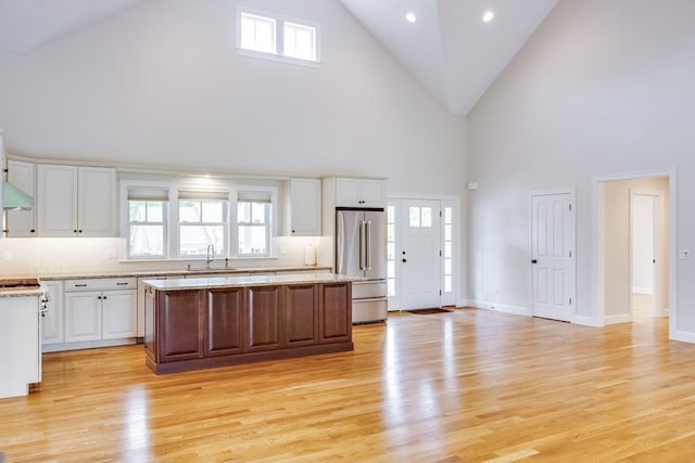 15 Hydrangea Cir, Falmouth, MA 02536 - kitchen featuring high end refrigerator, high vaulted ceiling, a sink, a kitchen island, and white cabinetry