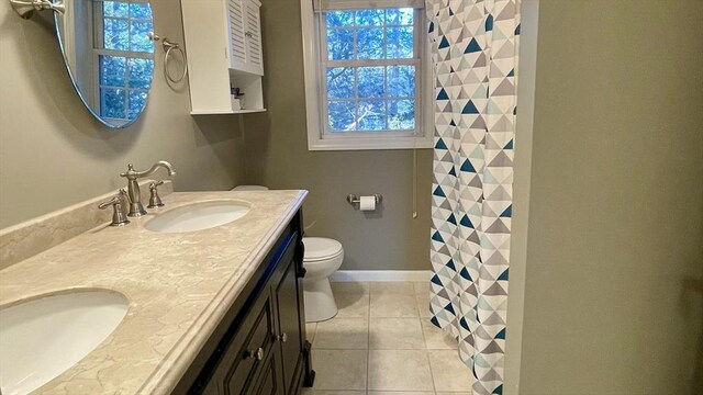 full bathroom with tile patterned flooring, baseboards, toilet, double vanity, and a sink