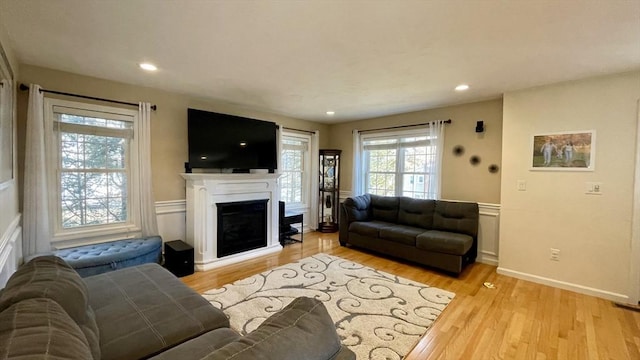 living area featuring recessed lighting, a fireplace, a wainscoted wall, and light wood finished floors