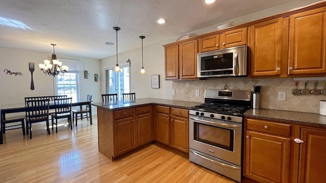 kitchen with a peninsula, brown cabinets, and appliances with stainless steel finishes