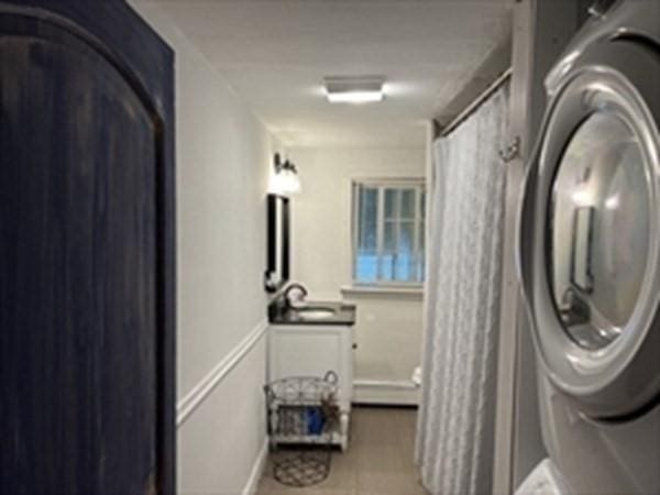 clothes washing area featuring stacked washing maching and dryer and tile patterned floors