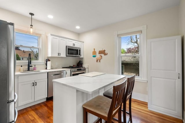 13 Darling St, Acushnet, MA 02743 - kitchen featuring appliances with stainless steel finishes, a sink, wood finished floors, a breakfast bar area, and recessed lighting