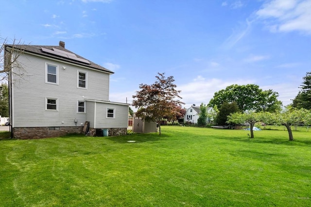 13 Darling St, Acushnet, MA 02743 - back of property with a lawn, roof mounted solar panels, and a chimney