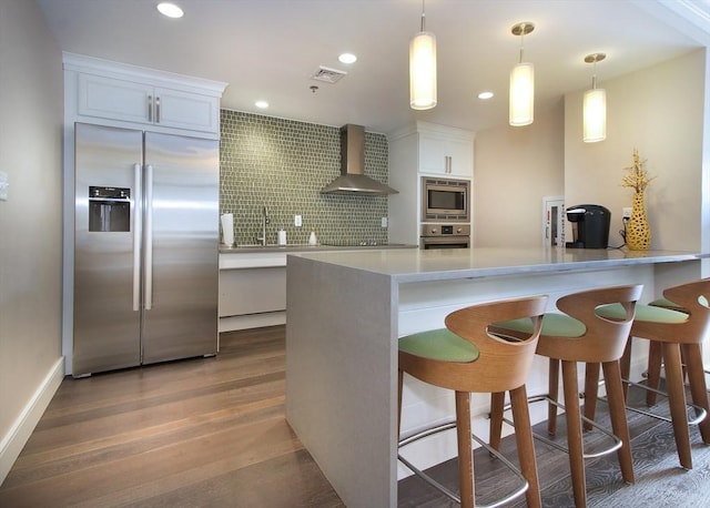 kitchen featuring built in appliances, visible vents, white cabinets, light countertops, and wall chimney exhaust hood