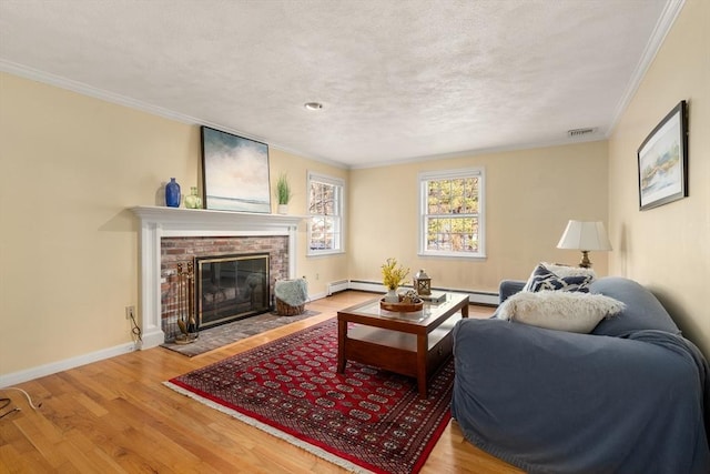 living room with hardwood / wood-style flooring, a baseboard heating unit, a fireplace, ornamental molding, and a textured ceiling