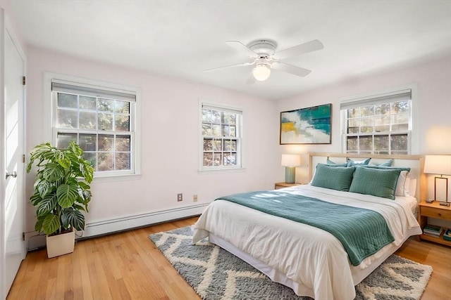 bedroom featuring a baseboard radiator, light wood-type flooring, and ceiling fan