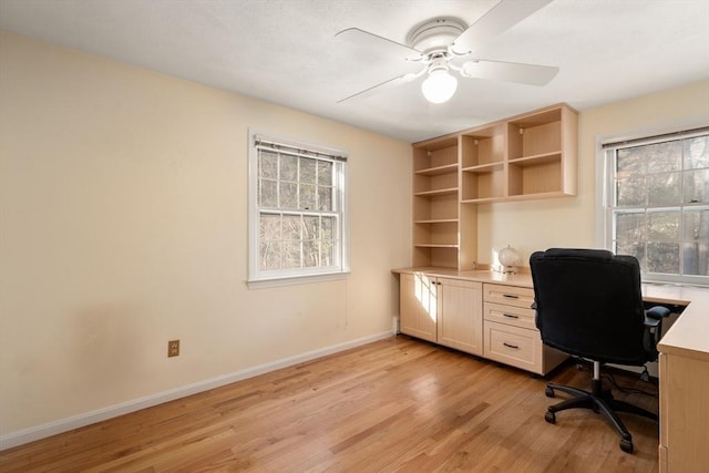 unfurnished office with ceiling fan, light wood-type flooring, and a wealth of natural light