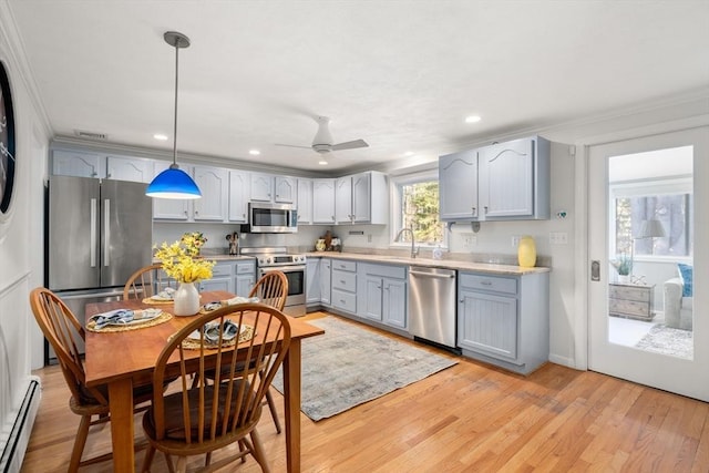 kitchen with sink, decorative light fixtures, light wood-type flooring, a baseboard radiator, and appliances with stainless steel finishes