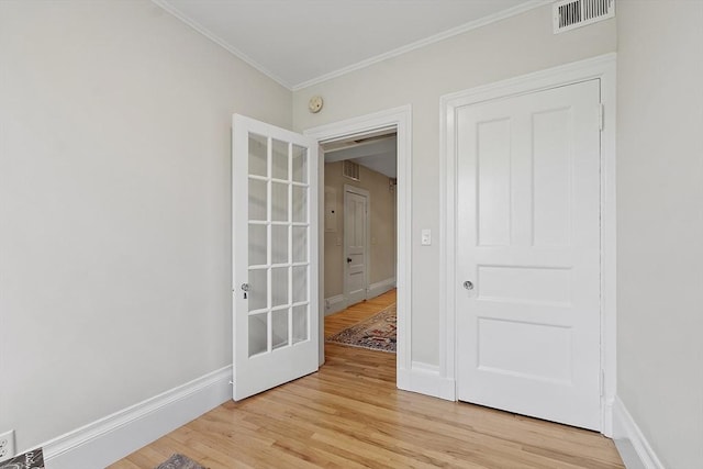 spare room featuring crown molding, baseboards, visible vents, and light wood-style flooring
