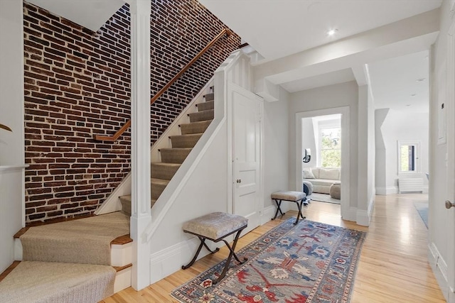 stairs featuring baseboards, wood finished floors, and brick wall