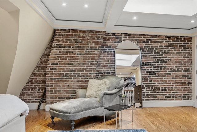 living area with baseboards, brick wall, and wood finished floors