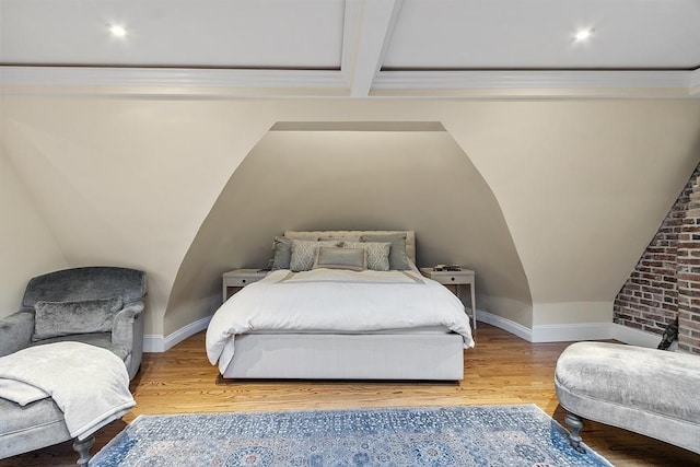 bedroom with baseboards, wood finished floors, and lofted ceiling