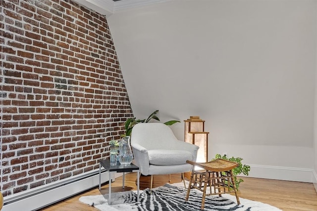 sitting room featuring ornamental molding, a baseboard heating unit, brick wall, and wood finished floors