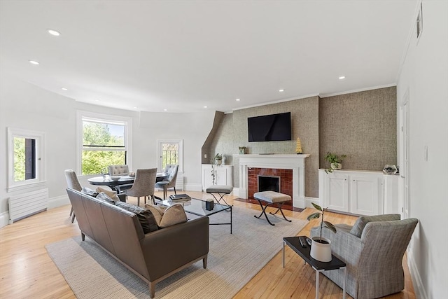 living room with light wood-style floors, radiator, a brick fireplace, and baseboards
