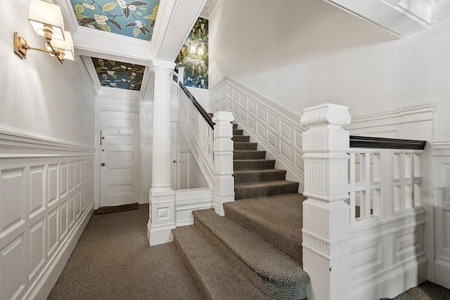 staircase featuring carpet, a decorative wall, and a wainscoted wall