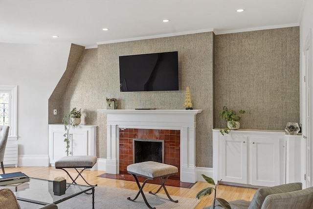 living area featuring crown molding, recessed lighting, a tiled fireplace, and light wood-type flooring