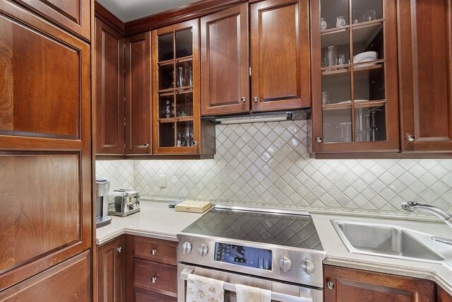 178 Commonwealth Unit 7, Boston, MA 02116 - kitchen with glass insert cabinets, light countertops, stainless steel electric stove, tasteful backsplash, and a sink