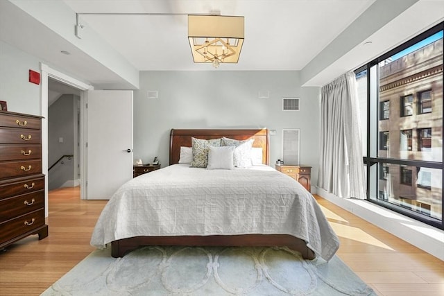 bedroom with multiple windows, light hardwood / wood-style flooring, and a notable chandelier