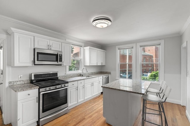 117 Babson St, Boston, MA 02126 - kitchen featuring appliances with stainless steel finishes, light wood-style floors, crown molding, white cabinetry, and light stone countertops