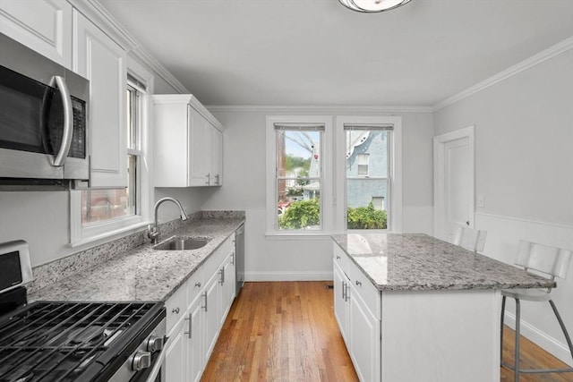 117 Babson St, Boston, MA 02126 - kitchen with appliances with stainless steel finishes, a kitchen island, a kitchen breakfast bar, white cabinetry, and light wood-style floors