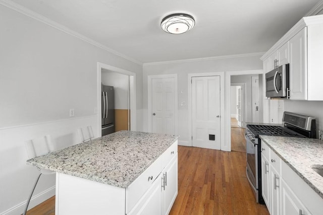 117 Babson St, Boston, MA 02126 - kitchen featuring stainless steel appliances, ornamental molding, white cabinetry, wood finished floors, and light stone counters