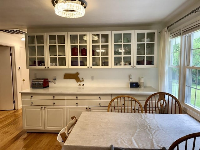 51 Karen Rd, Framingham, MA 01701 - kitchen featuring wood finished floors, white cabinetry, glass insert cabinets, and healthy amount of natural light