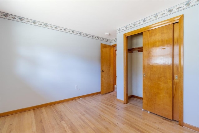 unfurnished bedroom featuring a closet, baseboards, and light wood-style floors