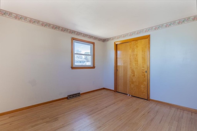 empty room with visible vents, baseboards, and light wood finished floors