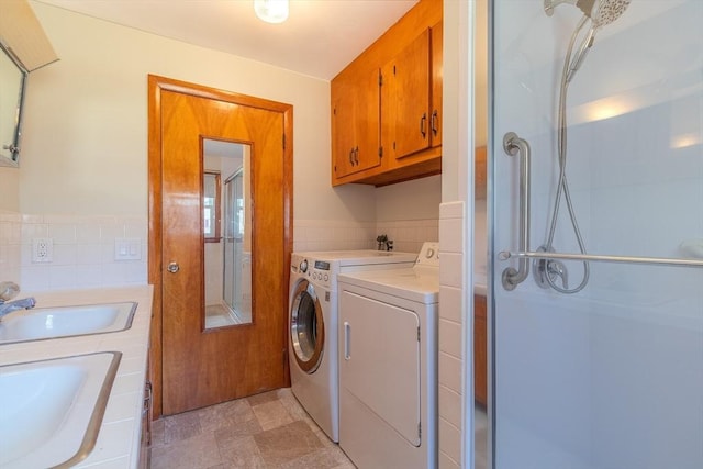 clothes washing area with washing machine and clothes dryer, laundry area, tile walls, and a sink