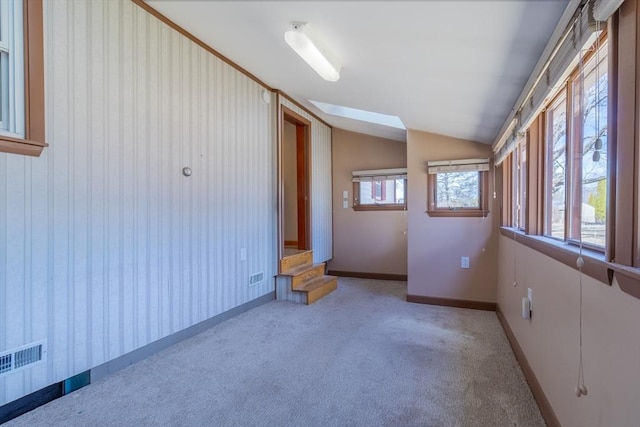 spare room with visible vents, lofted ceiling, carpet flooring, wallpapered walls, and baseboards