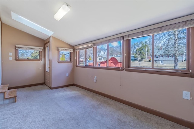 spare room with vaulted ceiling, baseboards, and light carpet