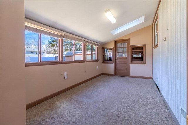 spare room featuring lofted ceiling with skylight, baseboards, and carpet floors