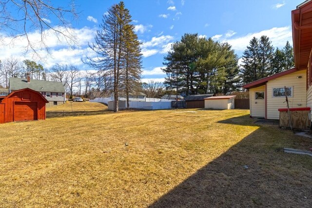 view of yard featuring an outdoor structure, a storage unit, and fence