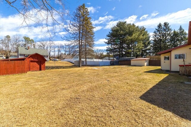 view of yard featuring an outbuilding, a storage unit, and fence