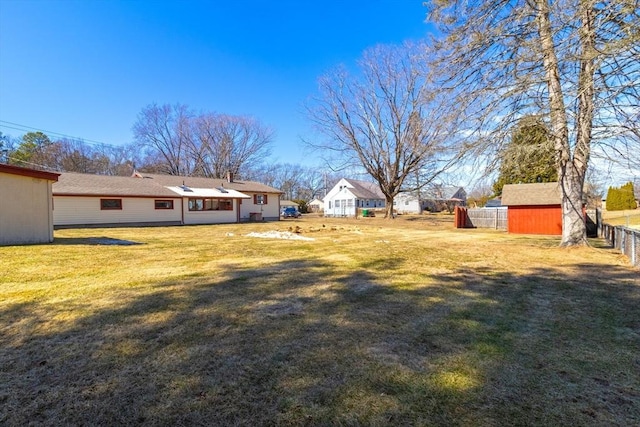 view of yard with an outdoor structure, a shed, and fence