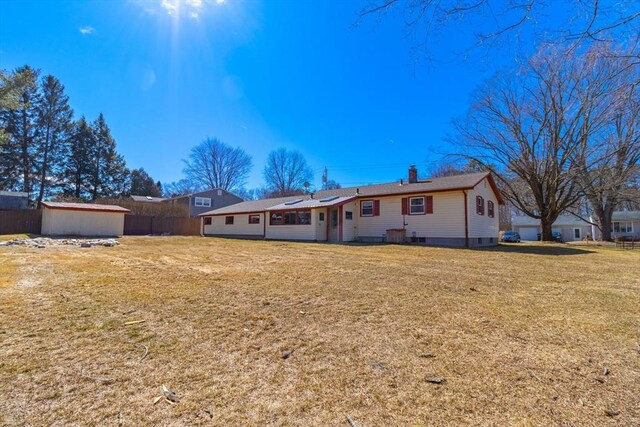 back of property with a yard, fence, and a chimney