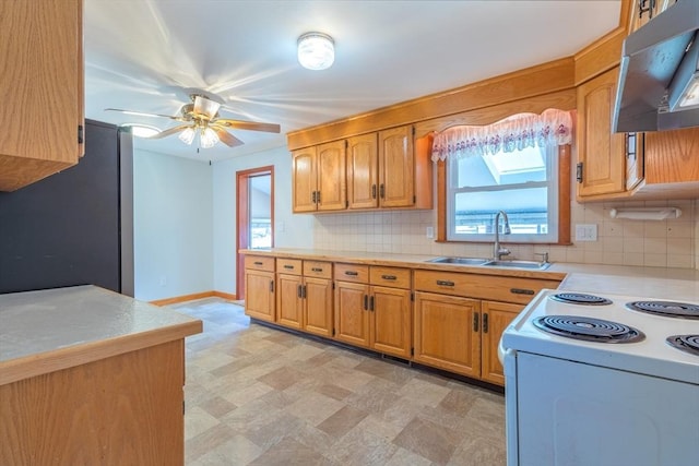 kitchen featuring under cabinet range hood, freestanding refrigerator, light countertops, and a sink