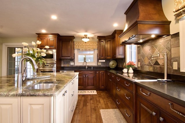 kitchen featuring dark wood-type flooring, black electric stovetop, custom exhaust hood, and sink