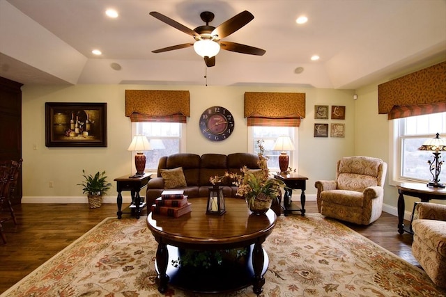 living room featuring dark wood-type flooring, a raised ceiling, and ceiling fan