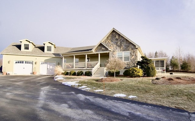 view of front facade with a front yard, covered porch, and a garage