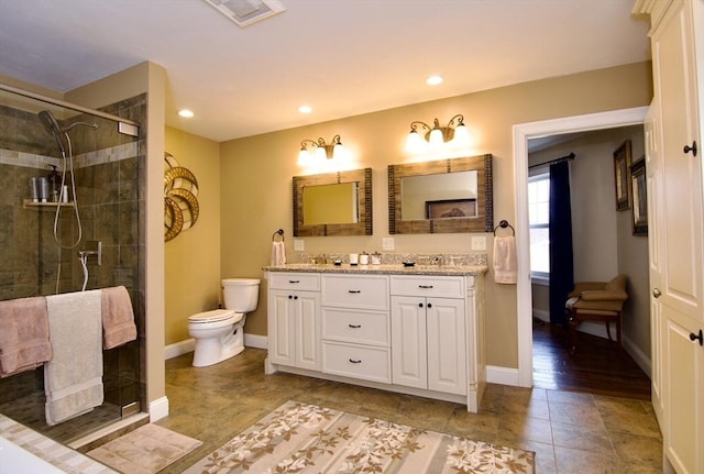 bathroom with toilet, tile patterned floors, vanity, and a shower with shower door