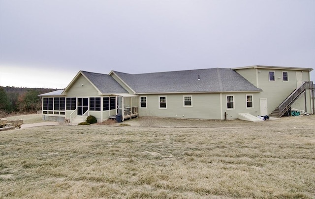 back of property with a sunroom and a lawn