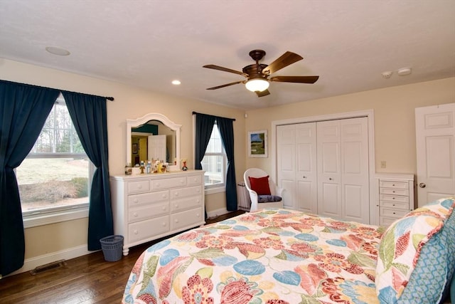 bedroom featuring ceiling fan, a closet, dark hardwood / wood-style flooring, and multiple windows