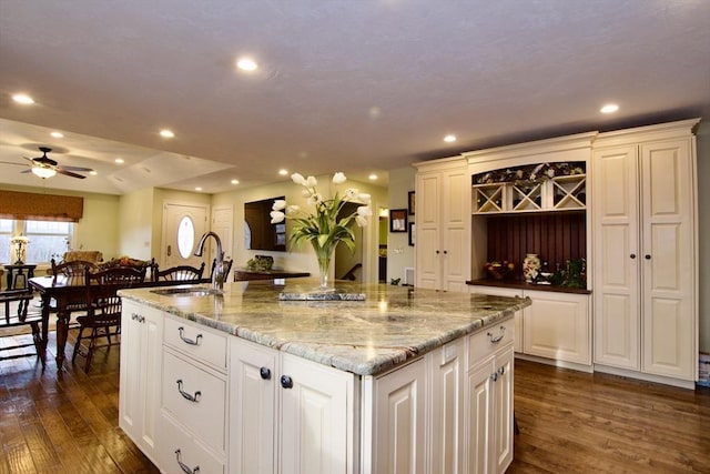 kitchen with white cabinets, dark wood-type flooring, sink, and a large island