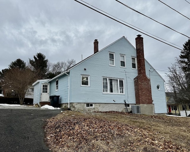 view of home's exterior featuring entry steps, a chimney, and central AC unit