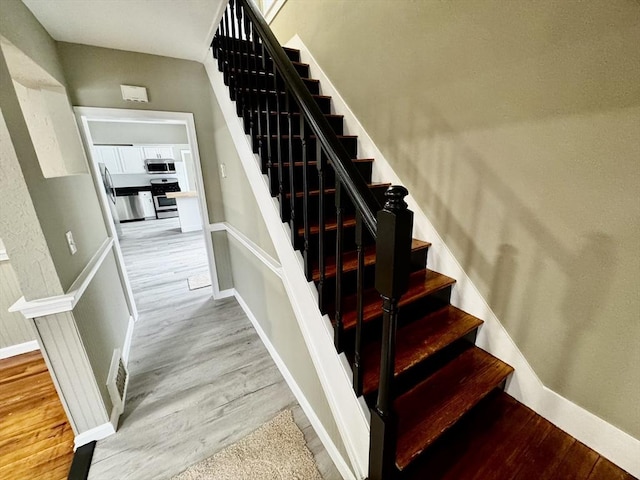 staircase featuring baseboards and wood finished floors