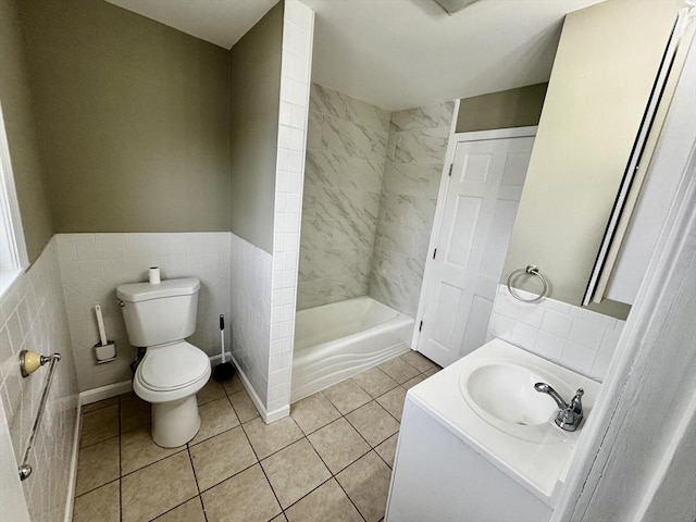 full bath with a wainscoted wall, tile walls, toilet, vanity, and tile patterned flooring